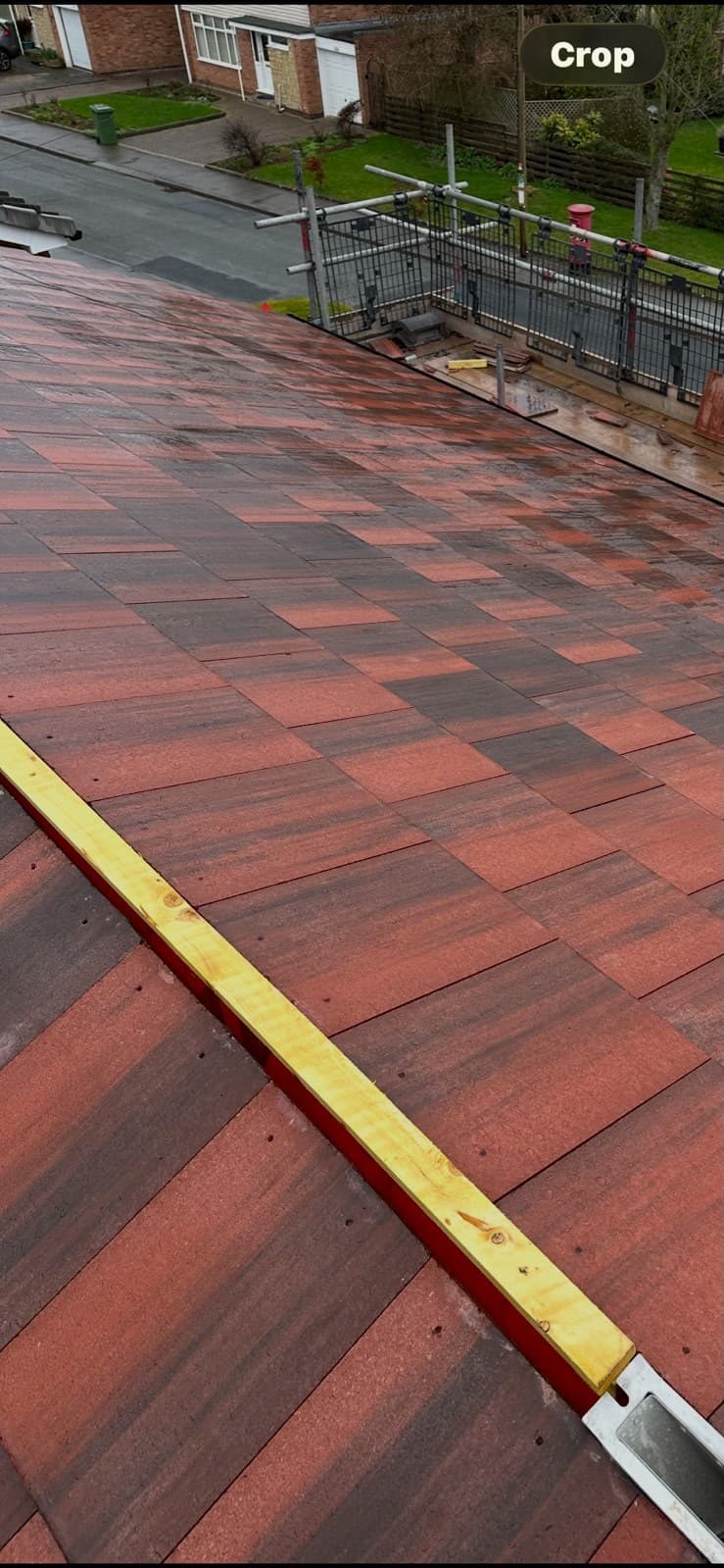 Measuring tape across new red roof tiles during installation