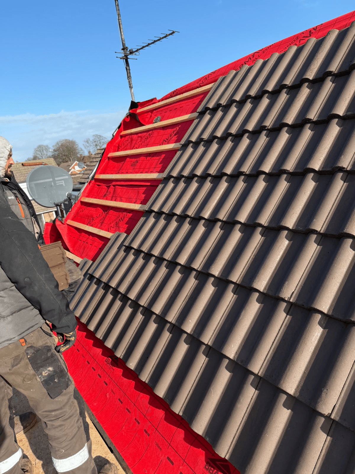 Concrete roof tiles half-laid on red membrane